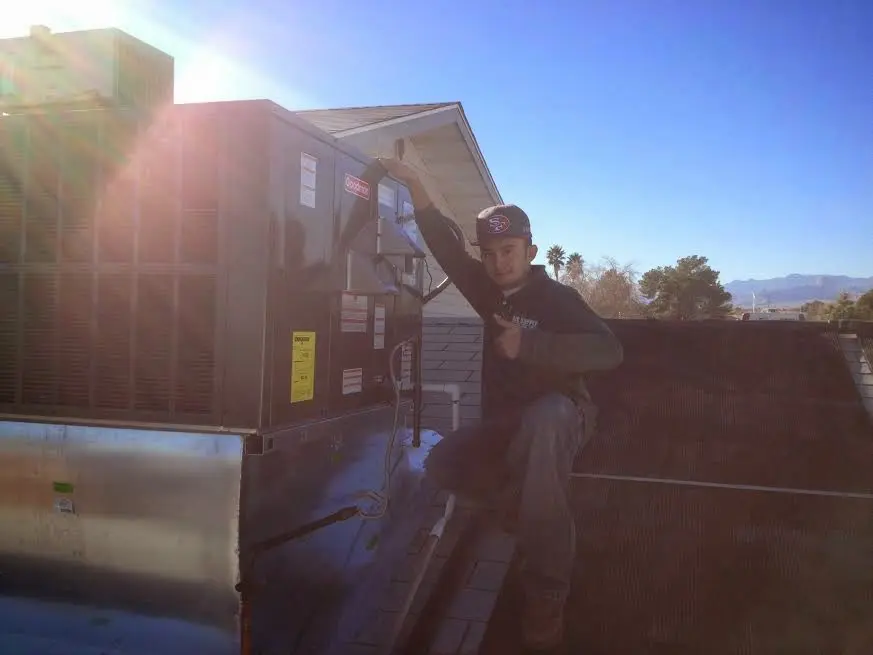 HVAC technician performing Air Duct Cleaning on a rooftop unit in Boone